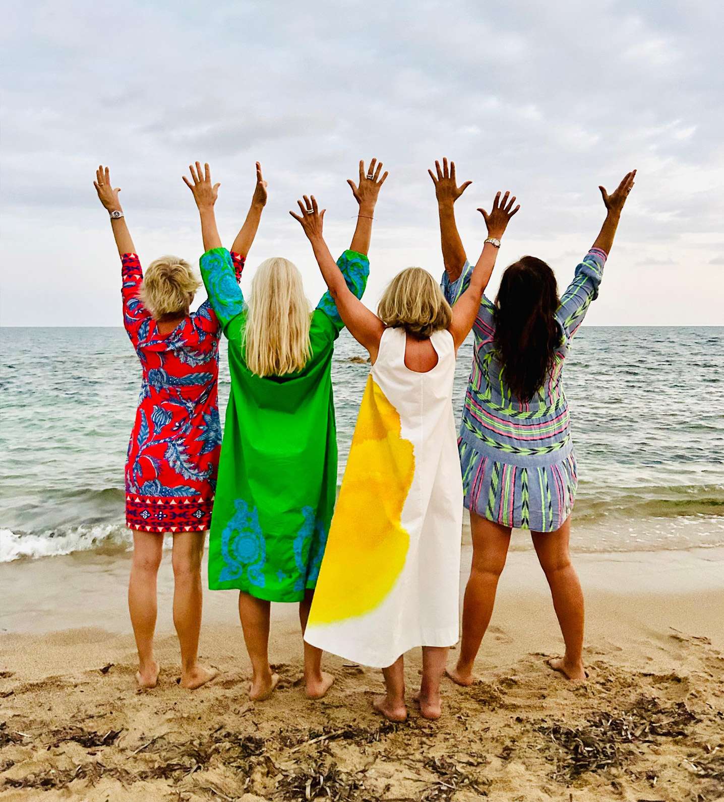 Mehrere Frauen stehen am Strand und machen Yoga-Übungen